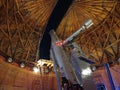 A telescope at Lowell Observatory with a view of Orion's belt and other stars visible in the sky out the window